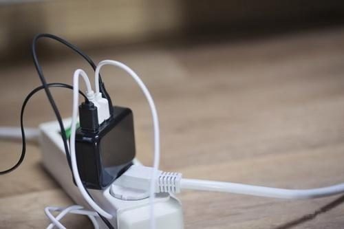 Several chargers and cables sharing a power strip against a wall