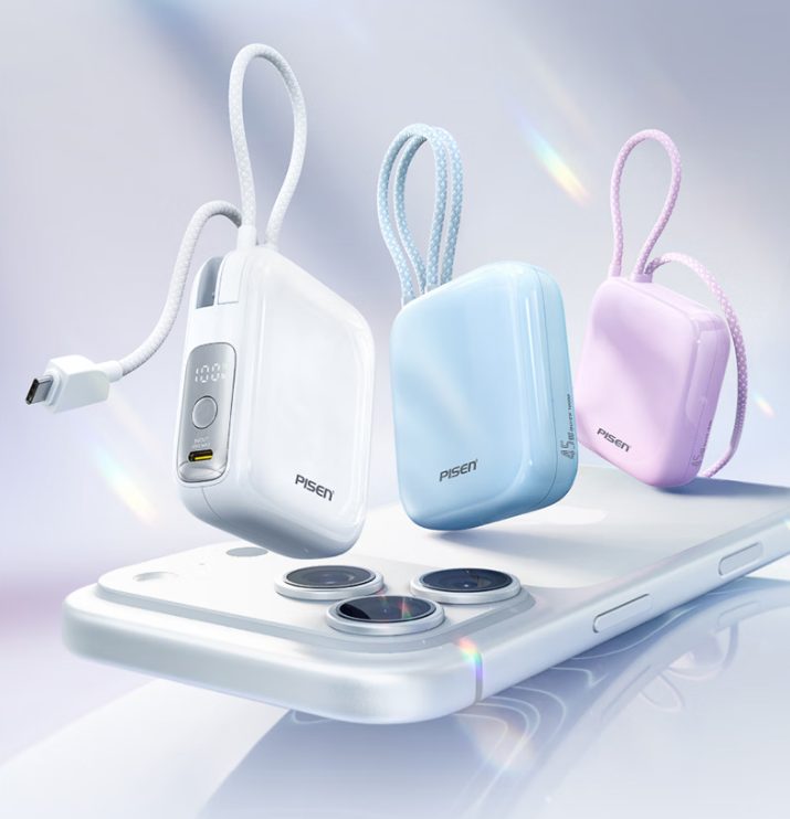 Three compact power banks in pale finishes beside a smartphone