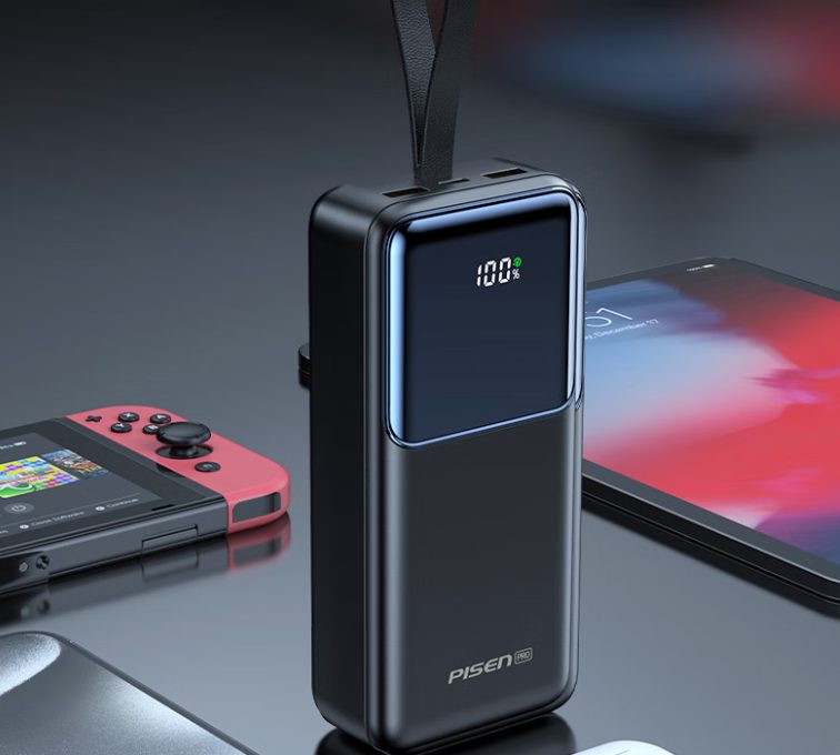 A tall power bank with a status display charging a handheld console and a phone
