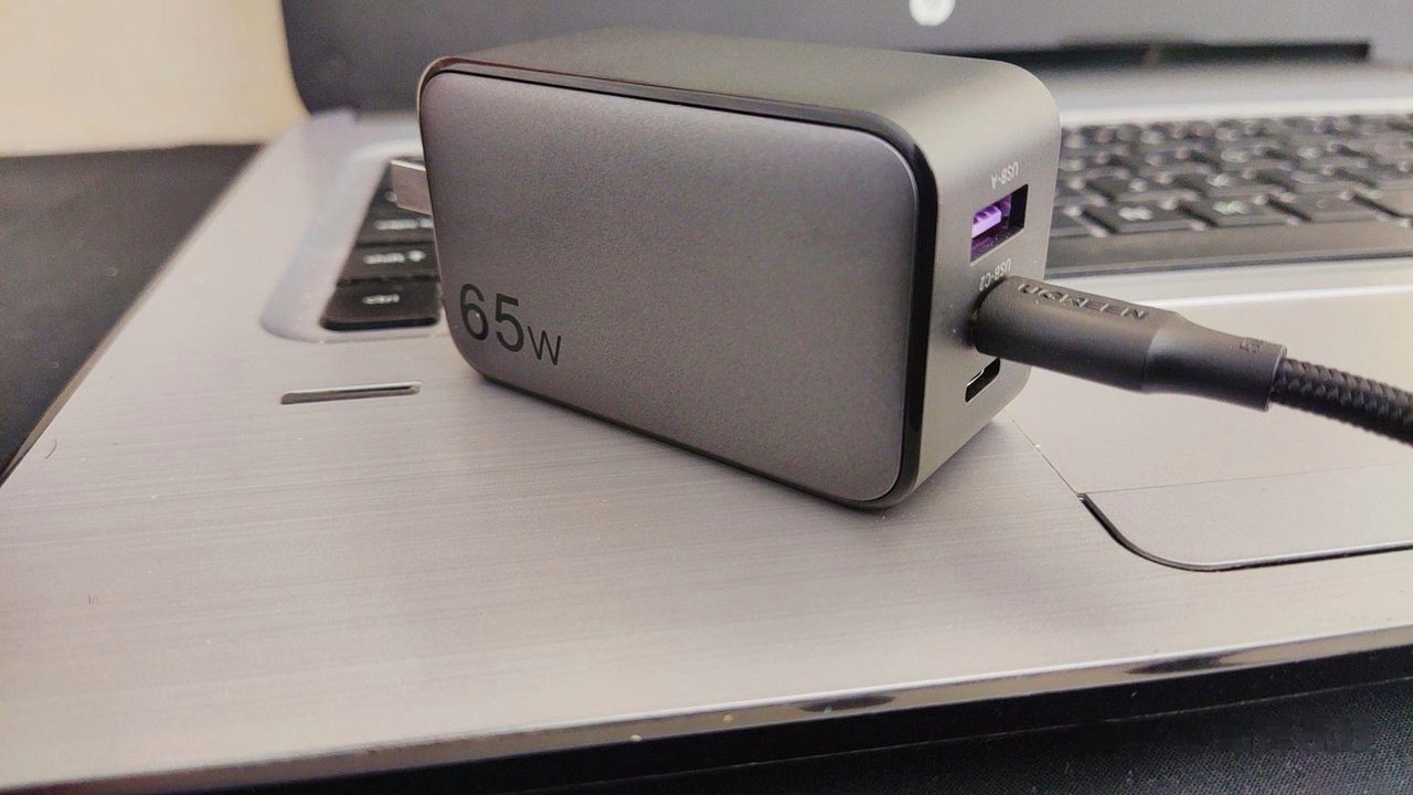 A multi-port charger resting next to the laptop it is expected to power