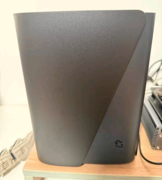 A rounded black NAS appliance photographed on a wooden shelf