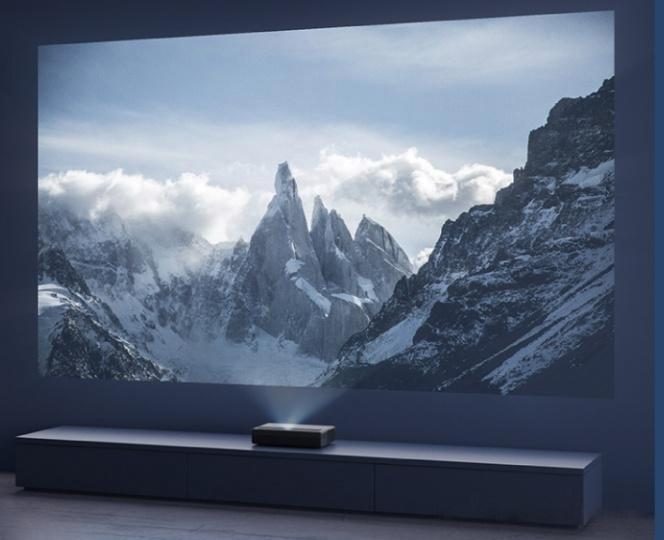 A projector casting a wide image onto a wall across a dark room