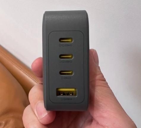 A four-output wall charger held in one hand for scale