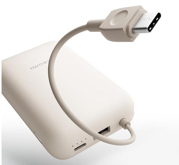 A slim power bank with its bundled cable laid out on a plain surface