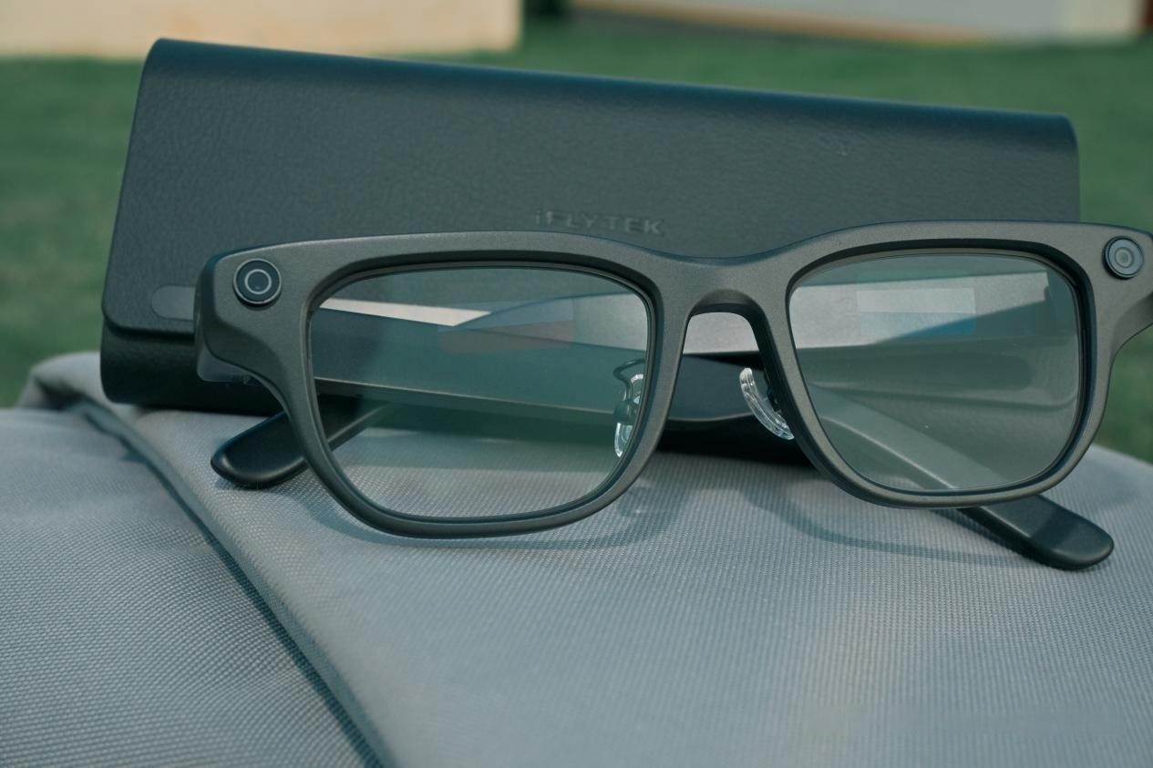 Smart glasses resting on a closed laptop beside their case