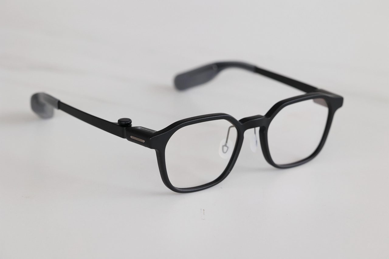 Front view of a slim black smart glasses frame with clear lenses